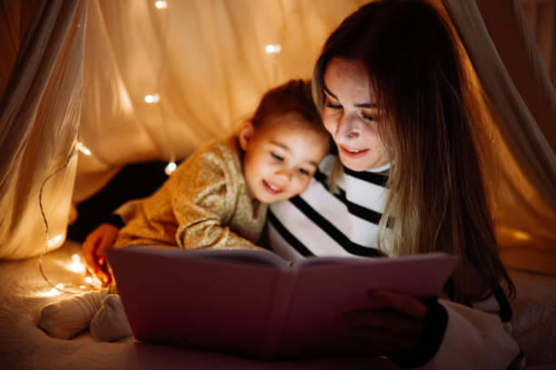 istock Mother and child reading book in bed before going to sleep 1360435772
