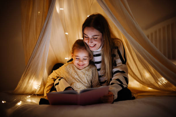 istock Mother and child reading book in bed before going to sleep 1360435810
