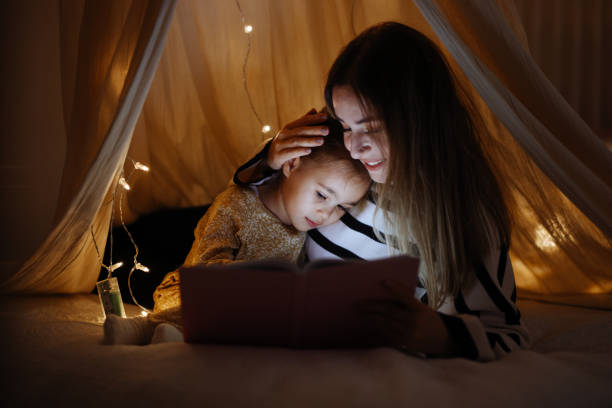istock Mother and child reading book in bed before going to sleep 1360435821