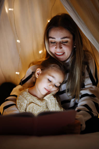 istock Mother and child reading book in bed before going to sleep 1360435854