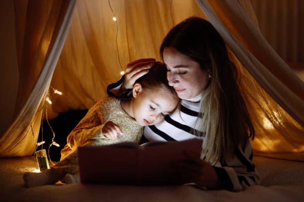 istock Mother and child reading book in bed before going to sleep 1360435931