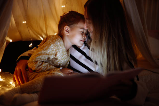 istock Mother and child reading book in bed before going to sleep 1360436467