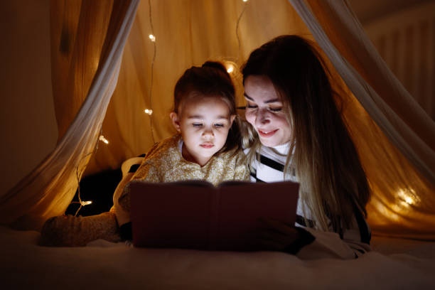 istock Mother and child reading book in bed before going to sleep 1360436509