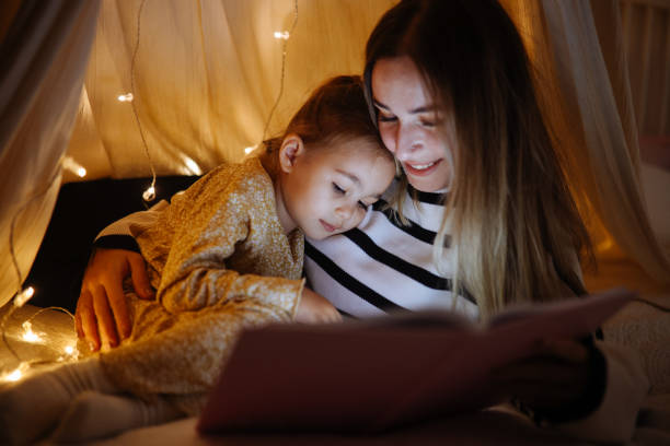 istock Mother and child reading book in bed before going to sleep 1360436547