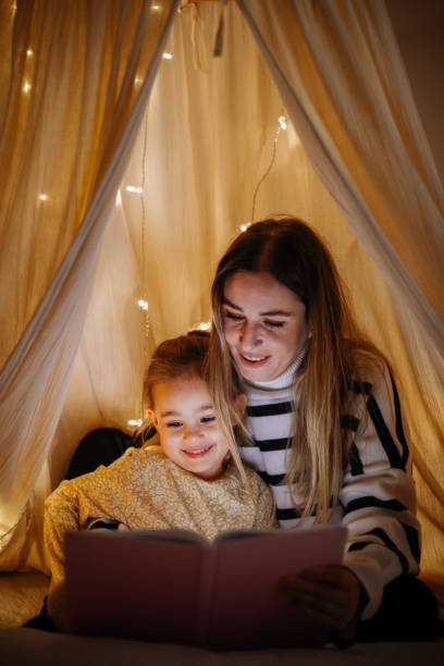 istock Mother and child reading book in bed before going to sleep 1360436568