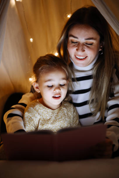 istock Mother and child reading book in bed before going to sleep 1360436592