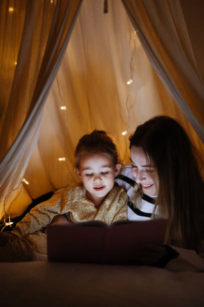 istock Mother and child reading book in bed before going to sleep 1360436623