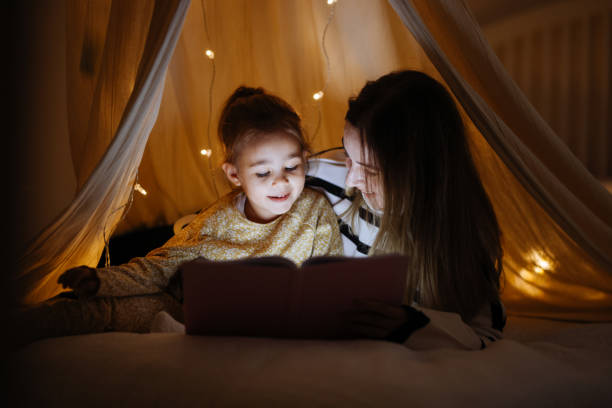 istock Mother and child reading book in bed before going to sleep 1360436666