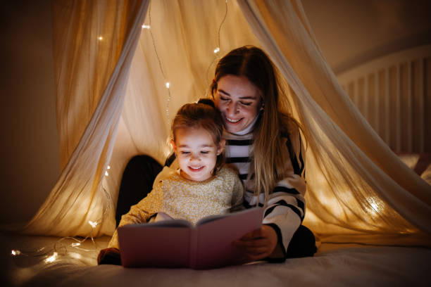 istock Mother and child reading book in bed before going to sleep 1360436690
