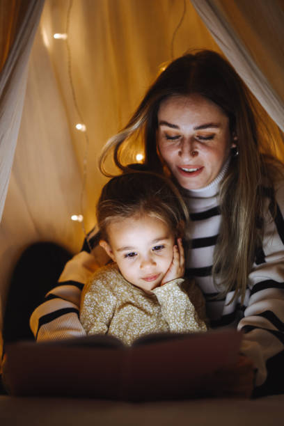 istock Mother and child reading book in bed before going to sleep 1360436706
