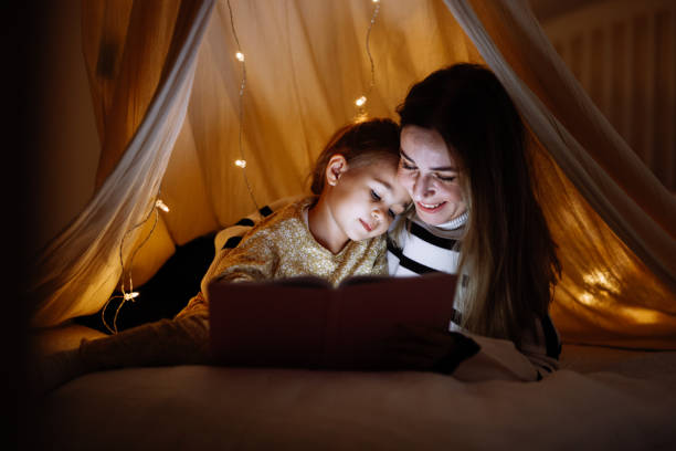 istock Mother and child reading book in bed before going to sleep 1360436720
