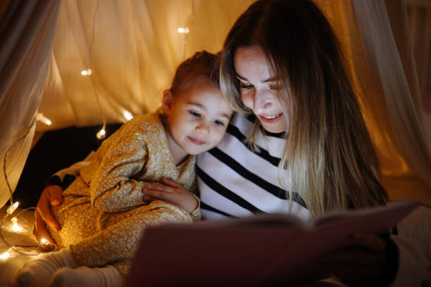 istock Mother and child reading book in bed before going to sleep 1360436729