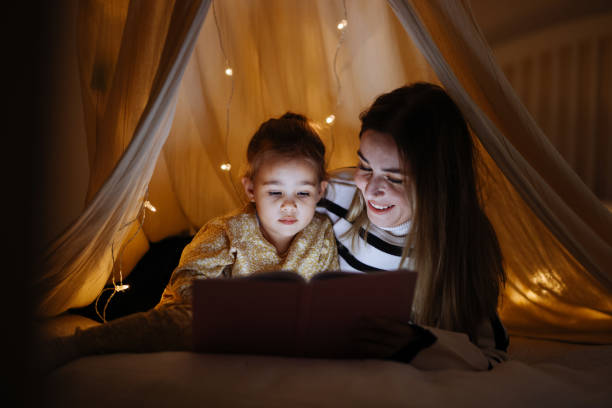 istock Mother and child reading book in bed before going to sleep 1360436738