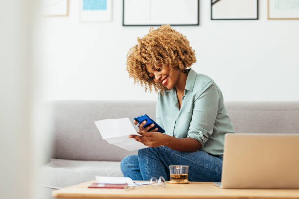 home office: an afro-american woman using a mobile phone - rekening stockfoto's en -beelden