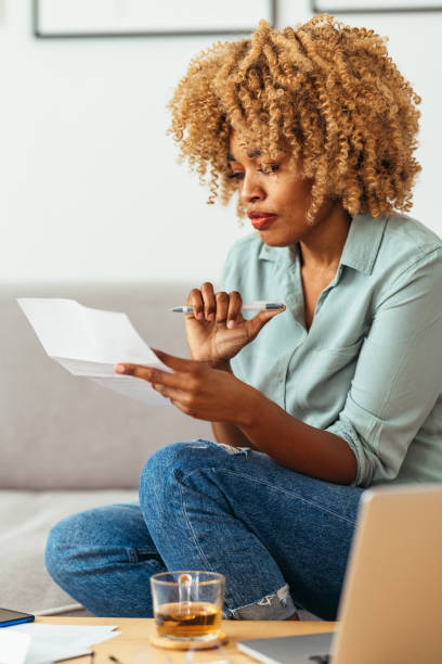 istock Home Office: An Afro-American Woman Looking at a Document 1360438527