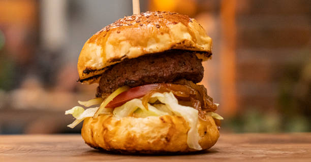 istock Tasty grilled burger with lettuce and mayonnaise , rustic wooden table 1360442846