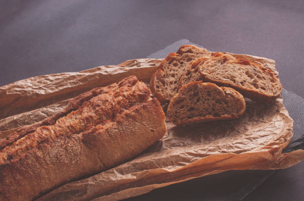 istock Rustic bread, beautiful golden crust, sliced bread lying on black board 1360444550