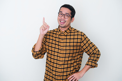 Adult Asian man wearing yellow flannel shirt smiling happy after got new idea