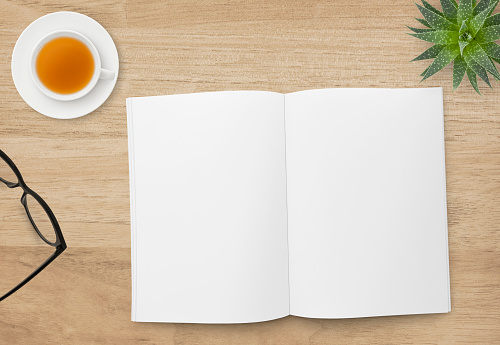 Wood table top with blank open book, eyeglasses, tea and succulent plant