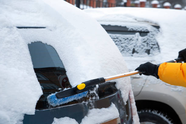istock A man cleans the car from snow with a brush. Climate, weather. 1360459263