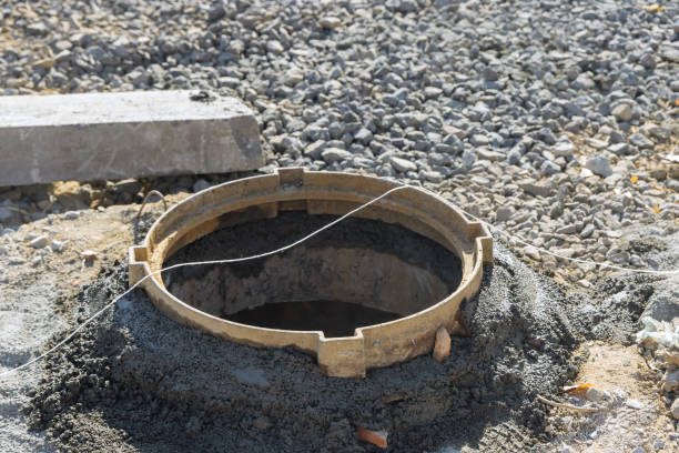 istock Sewerage construction with utility worker installing underground well manhole sewage 1360461131