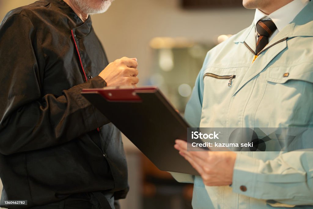 Asian man inspecting restaurant equipment Coveralls Stock Photo
