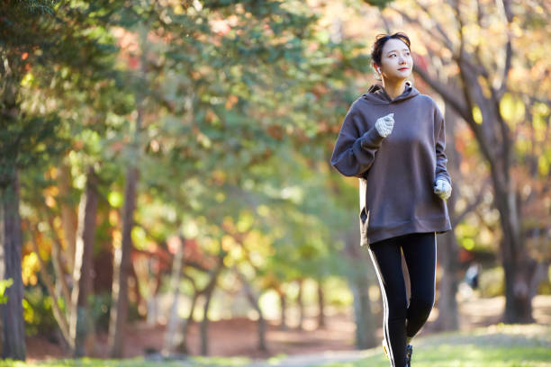 公園で運動している若いアジアの女性 - 競歩 ストックフォトと画像