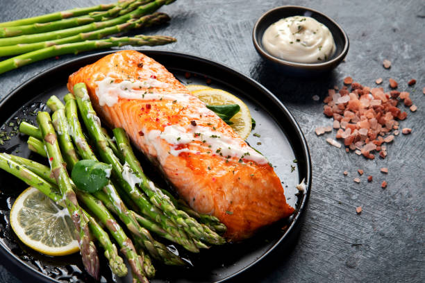 istock Baked salmon with asparagus on gray background. 1360470428