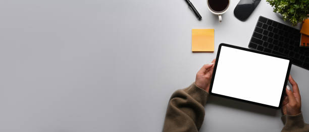 istock Overhead view creative woman holding digital tablet with empty screen on white table. 1360471896