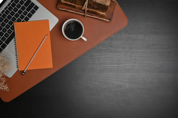 Computer laptop, notebook and coffee cup on black wooden table.