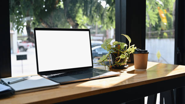istock Computer laptop with white screen, notebook and houseplant on wooden table. 1360471927