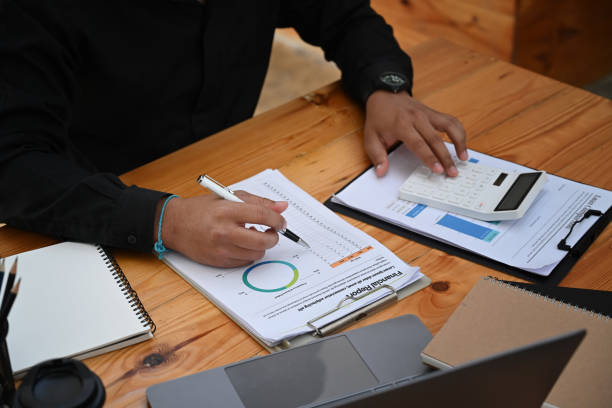 istock Male accountant using calculator and analyzing financial graph at office desk. 1360471929