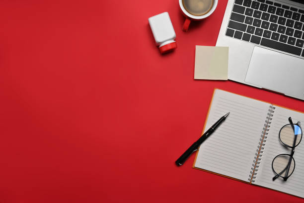 istock Top view computer laptop, notebook, glasses and pill bottle on red background. 1360471938