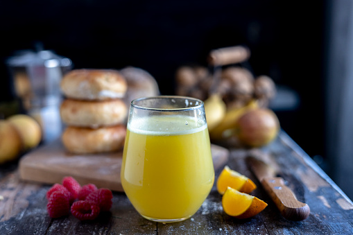 still life: fresh orange juice and sweet bagel on table
