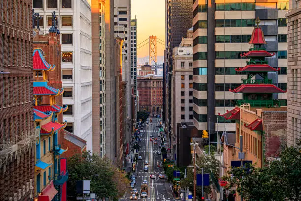 Famous view of California Street near China Town and the Financial District, with Chinese pagoda towers and the Bay Bridge at sunset in San Francisco