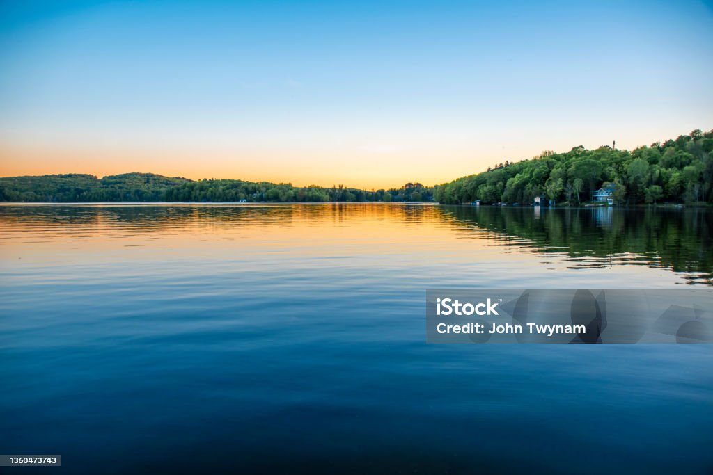 Calm Water on a Clear Night A lake house sits on the shore of the calm water of Peninsula Lake near Huntsville, Ontario on a clear summer evening. Lake Stock Photo
