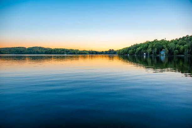 Calm Water on a Clear Night A lake house sits on the shore of the calm water of Peninsula Lake near Huntsville, Ontario on a clear summer evening. calm water stock pictures, royalty-free photos & images