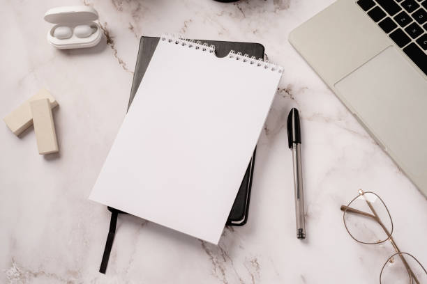istock Top view desktop blank calendar, notebook and laptop on light gray marble background 1360478473