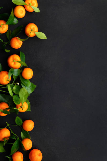 istock Mandarins or clementines with leaves on a black background. Top view. 1360479260