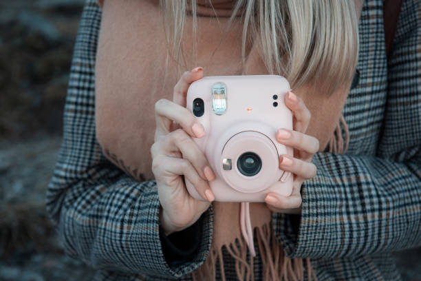 istock Woman hands holding a pink instax camera 1360480199