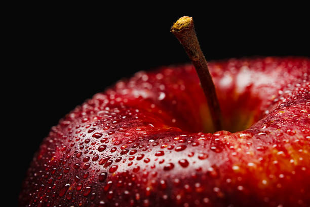 красное яблоко с каплями воды крупным планом на темном фоне - wet apple стоковые фото и изображения