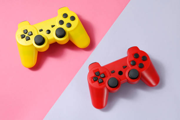 Game control. Yellow and red two game control,  on pink and purple background. The concept of the competition. game controller stock pictures, royalty-free photos & images