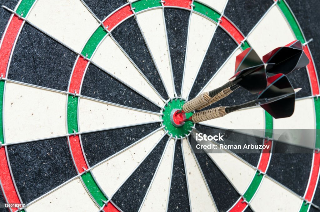 A game of darts. Three darts hit the center. Space for text. A game of darts. Dart Stock Photo