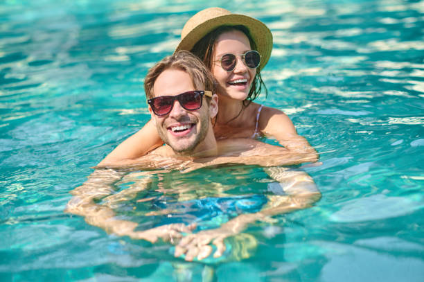 istock Young happy couple spending time in a swimming pool 1360485965