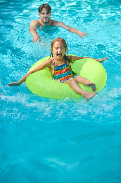 istock Dad teaching his daughter swimming in a swimming pool 1360486064