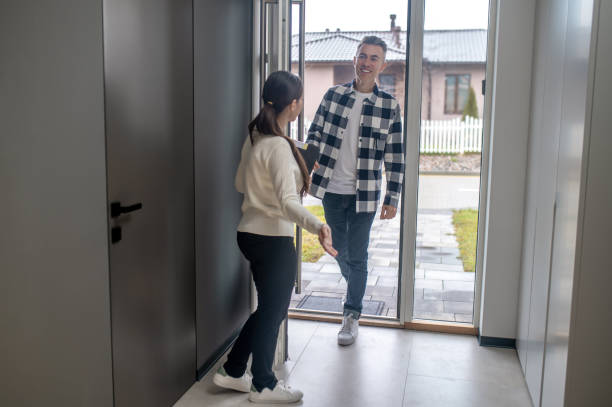 istock Woman with back to camera inviting man to home 1360492018