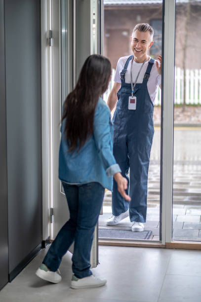 istock Woman with back to camera inviting plumber to home 1360492051