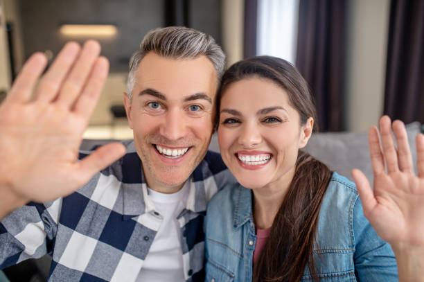istock Man and woman with raised hand looking at camera 1360492106