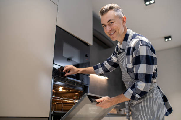 istock Man turning toggle switch of oven looking at camera 1360492435