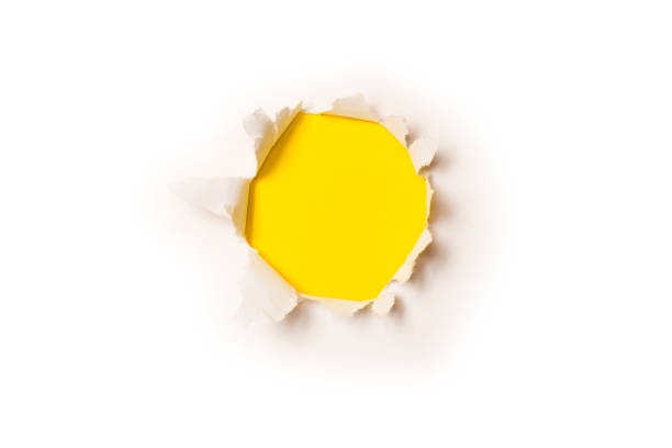 istock A hole in a white paper on a yellow background. 1360494425